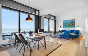 Enjoy a panoramic ocean view from the spacious dining area, featuring a comfortable seating area with a sofa and a large painting on the wall.