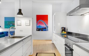 Enjoy cooking in this kitchen with a stainless steel sink, black pendant light, coffee maker, and stove.