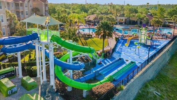 Parque acuático con toboganes y piscinas, rodeado de edificios y vegetación.