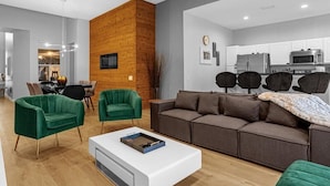 Una sala de estar moderna con una pared de acento de madera, una mesa de centro blanca y sillones verdes.