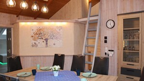 A wooden dining area with a table set for four, a ladder, a clock, and a cabinet with glassware. - Lovely home in Haren with sauna (Haren)