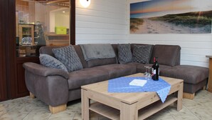 A cozy living area with a brown leather sofa, a wooden coffee table, and a painting of a beach scene on the wall. - Lovely home in Haren with sauna (Haren)