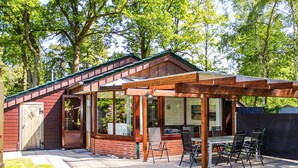 A wooden house with a covered patio, brick walls, and a door. - Lovely home in Haren with sauna (Haren)
