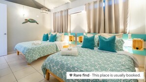 A hotel room with two beds, teal bedding, and a turtle mural. - Casa Tortuga | Beachfront Villa | Pool | Aguada PR (Aguada)