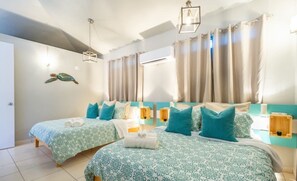 A hotel room with two beds, teal bedding, and a turtle mural.