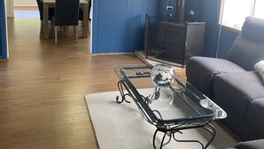 Een woonkamer met een blauwe muur, een flatscreen televisie, een glazen salontafel, een bank en een open haard.