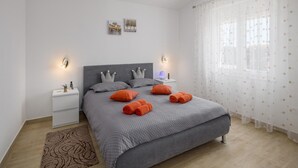 A neatly arranged bedroom with a large bed, two nightstands, a lamp, and a window with sheer curtains. - Gorgeous home in Barban (Barban)