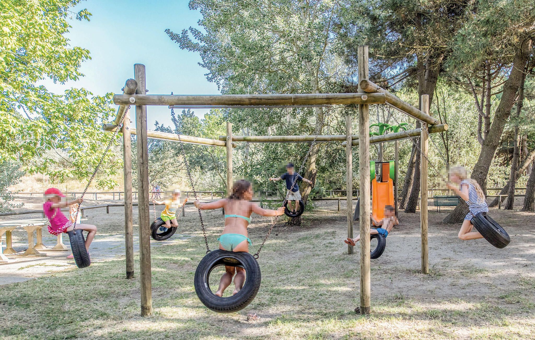 A playground with tire swings and a wooden structure.