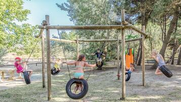 A playground with tire swings and a wooden structure.
