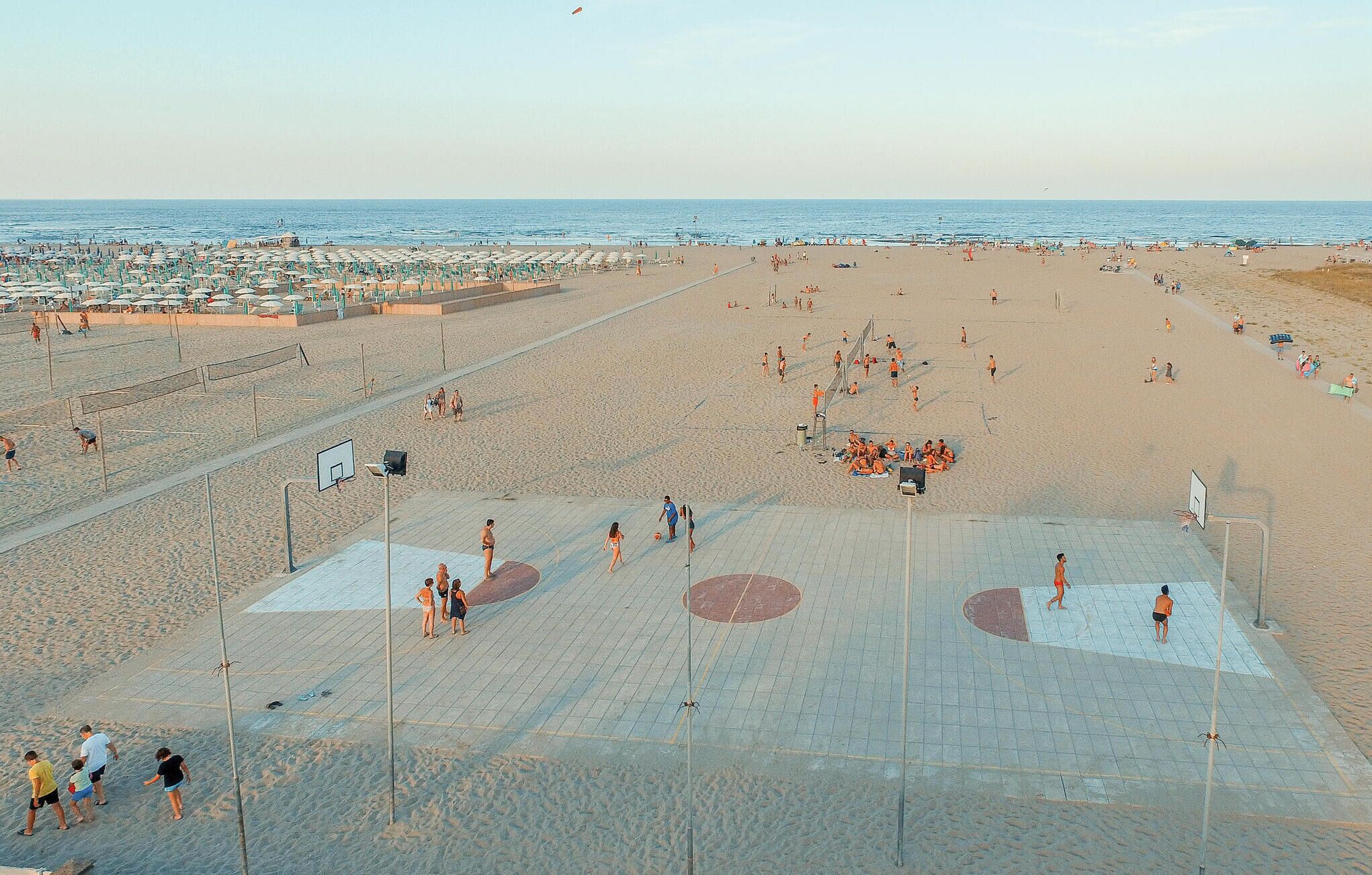 A beach with a basketball court and volleyball court.