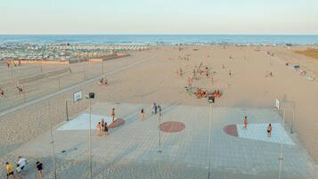 A beach with a basketball court and volleyball court.