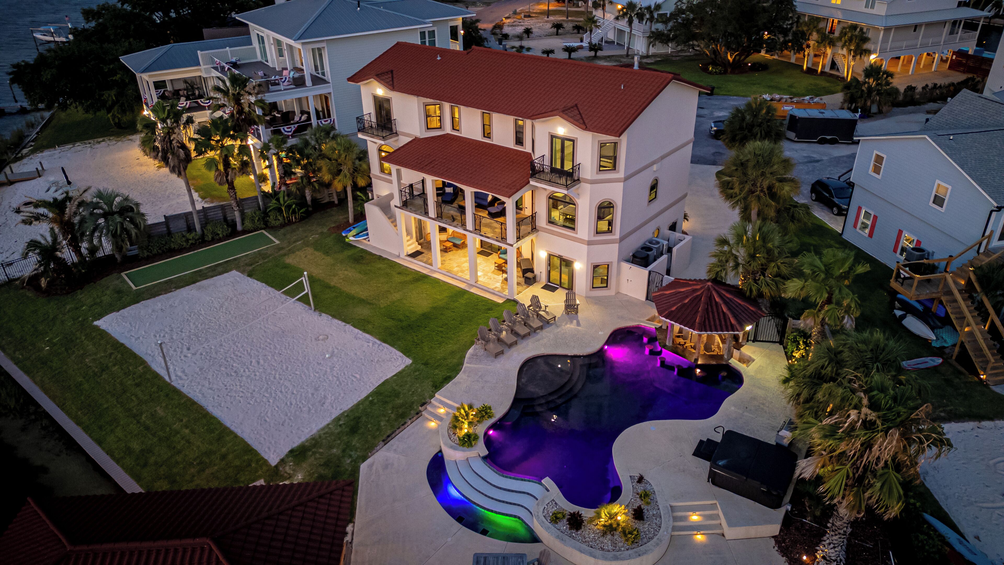 Une grande maison à deux étages dotée d’une piscine, d’un espace salon extérieur et d’une pelouse bien entretenue.