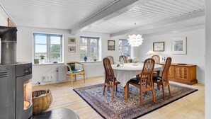 A dining area with a round table, wooden chairs, a patterned rug, and a modern pendant light.