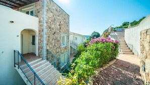 A narrow pathway flanked by stone buildings with a staircase leading to a higher level. - Amazing apartment in Baja Sardinia (Baja Sardinia)