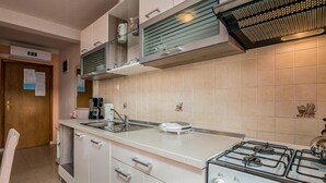 Une cuisine équipée d’une cuisinière à gaz, d’une machine à café et d’un évier.