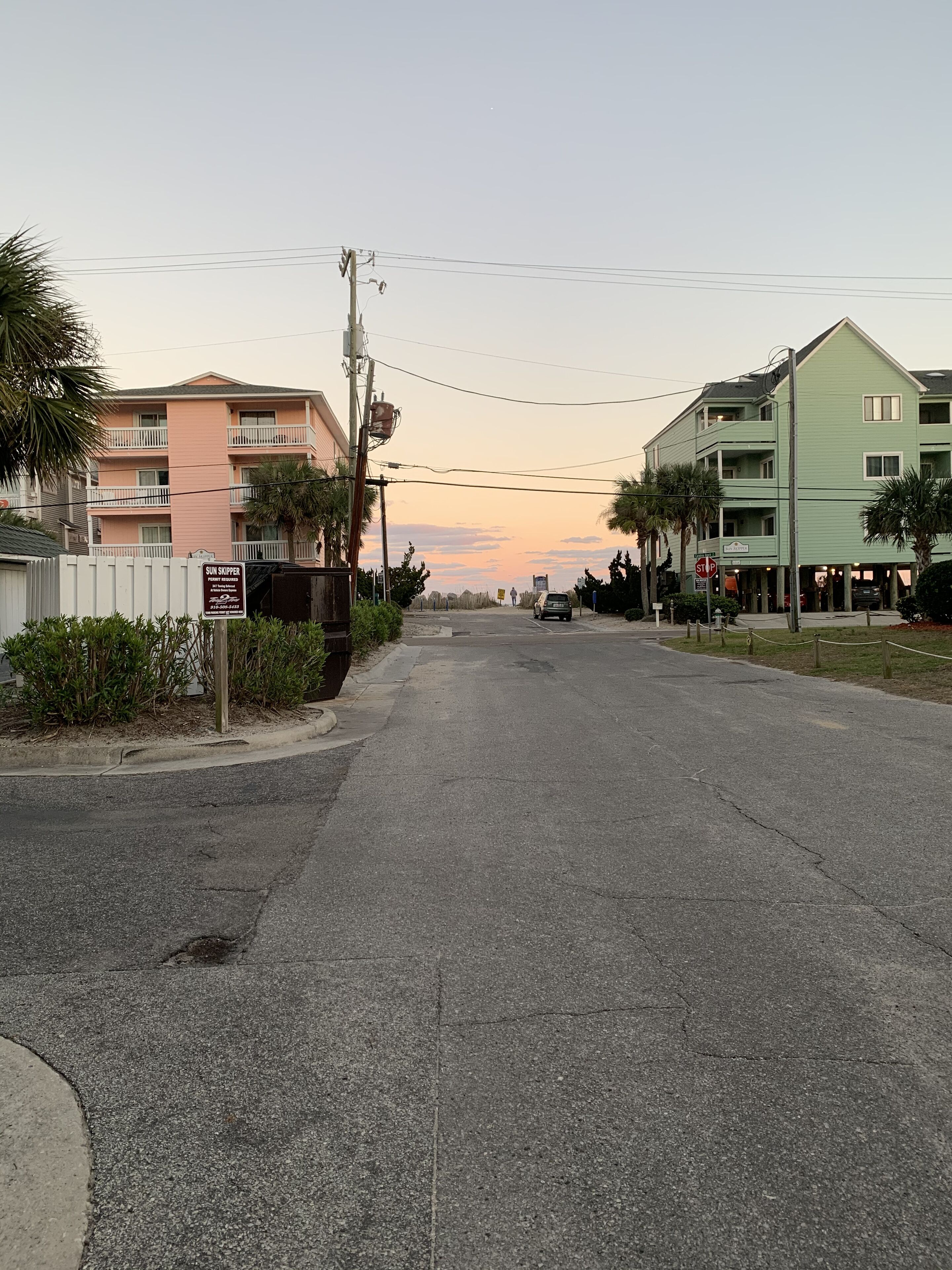 A street with a row of multi-story buildings, a stop sign, and a sign for 'Sun Skipper'.
