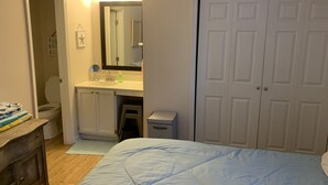 A bedroom with a bed, a dresser, a mirror, a sink, and a closet.