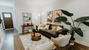 A living room with a sofa, armchairs, a coffee table, and a large plant.