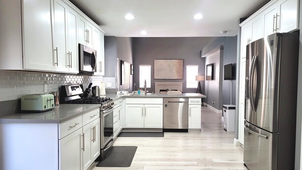 A modern kitchen with white cabinets, stainless steel appliances, and a central island. - Perfect Vegas Oasis with Gorgeous Yard/Spa and Pool, Remote Working & Vacation (Henderson)