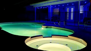 A swimming pool with a hot tub, surrounded by a covered patio with string lights. - Perfect Vegas Oasis with Gorgeous Yard/Spa and Pool, Remote Working & Vacation (Henderson)