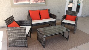 A patio area with wicker furniture, including a sofa and two chairs, and a glass coffee table. - Perfect Vegas Oasis with Gorgeous Yard/Spa and Pool, Remote Working & Vacation (Henderson)