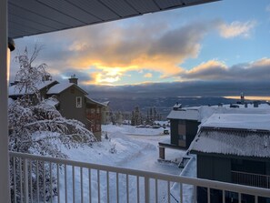 Paisagem nevada com uma casa e vista para montanhas distantes.