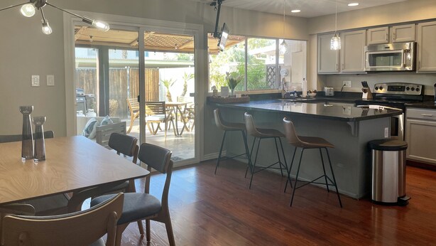 A modern kitchen with a central island, stainless steel appliances, and a sliding glass door leading to an outdoor patio. - Come fall in LOVE with Chateau MB (Scottsdale)