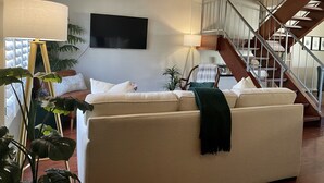 A living room with a sofa, a lamp, a TV, and a staircase. - Come fall in LOVE with Chateau MB (Scottsdale)