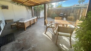 A covered patio area with a wooden table and chairs, a barbecue grill, and a concrete floor. - Come fall in LOVE with Chateau MB (Scottsdale)