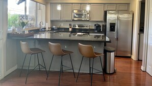 A modern kitchen with a central island, stainless steel appliances, pendant lighting, and a view of the outdoors. - Come fall in LOVE with Chateau MB (Scottsdale)