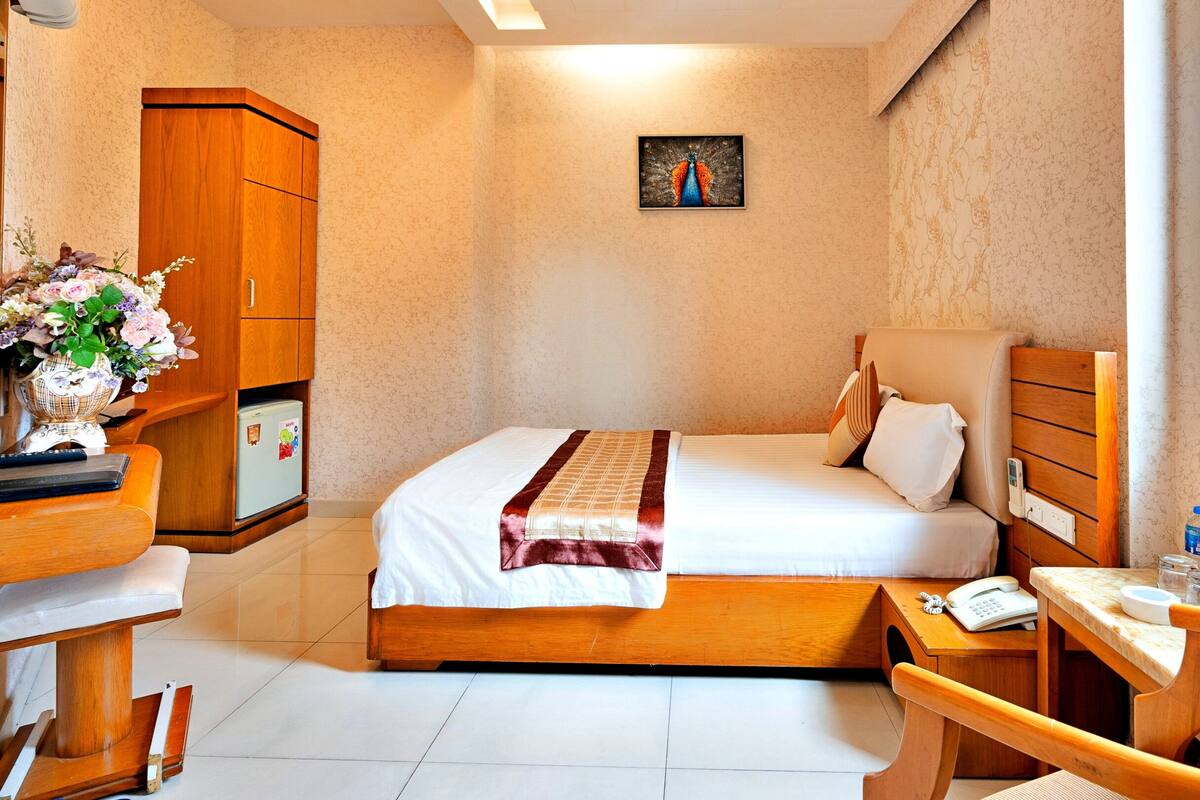 Ein Hotelzimmer mit Bett, Schreibtisch, Stuhl, Kleiderschrank und einem Bild an der Wand.