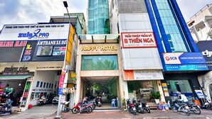 Ein Hotel Eingang mit einem Schild für Happy Hotel, einem 3M Geschäft und einem Schild mit dem Happy Hotel Schriftzug in Vietnamesisch.
