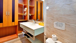 Ein Badezimmer mit Holzausstattung, einem weißen Waschbecken, einem Spiegel, einem Handtuchhalter und einer Toilette.