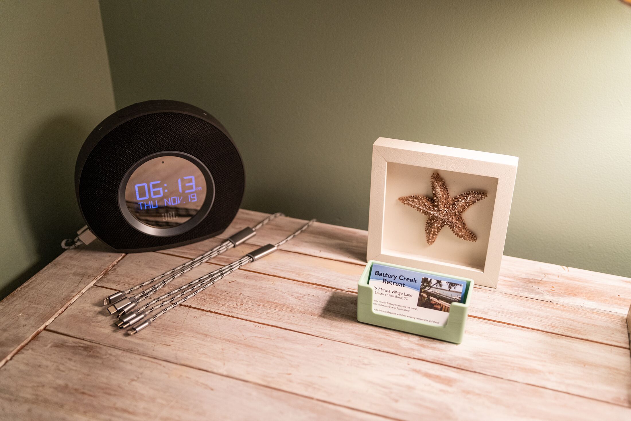 A wooden table with a digital clock, a starfish in a display case, and a sign for Battery Creek Retreat.