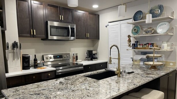 A modern kitchen with dark wooden cabinets, stainless steel appliances, a granite countertop, and bar stools. - Highest Elevation in Snowshoe. Home+Interior building renovated 2023.
 (Snowshoe)