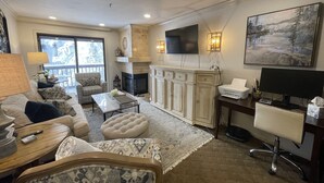 A living room with a fireplace, sofa, coffee table, and a television mounted on the wall. - Highest Elevation in Snowshoe. Home+Interior building renovated 2023.
 (Snowshoe)