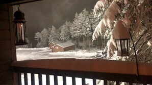 A snowy landscape with a cabin and trees, viewed from a balcony with a railing. - Highest Elevation in Snowshoe. Home+Interior building renovated 2023.
 (Snowshoe)