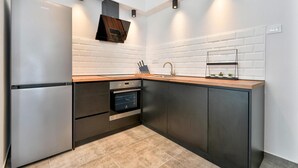 Een moderne keuken met een roestvrijstalen koelkast, een ingebouwde oven en een houten aanrecht.
