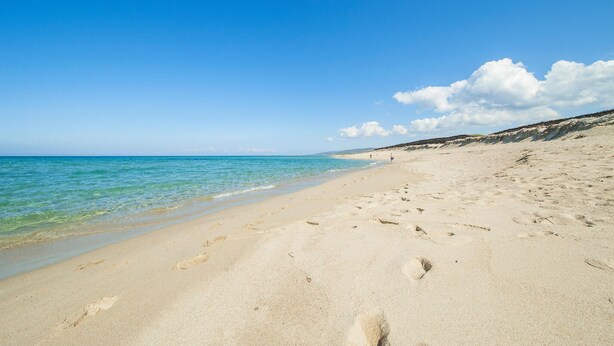 A wide sandy beach with clear blue water and a few footprints. - 2 bedroom lovely apartment in Badesi (Badesi)