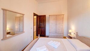 A hotel room with a large bed, two bedside tables with lamps, a wardrobe, and a mirror. - 2 bedroom lovely apartment in Badesi (Badesi)