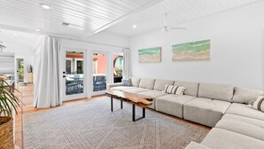 Ett rymligt vardagsrum med en stor beige soffa, ett soffbord i trä och en mönstrad matta.