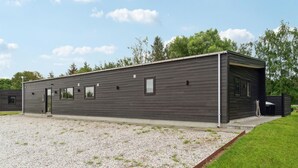 Moderni, yhden kerroksen talo, jossa on tumma julkisivu, sorapäällysteinen ajotie ja nurmialue.