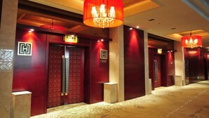 A hotel corridor with red doors, a patterned carpet, and chandeliers. - Long Xin International Hotel (Lanzhou)