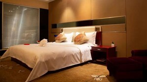 A hotel room with a large bed, a nightstand, a red chair, and a window with blinds. - Long Xin International Hotel (Lanzhou)