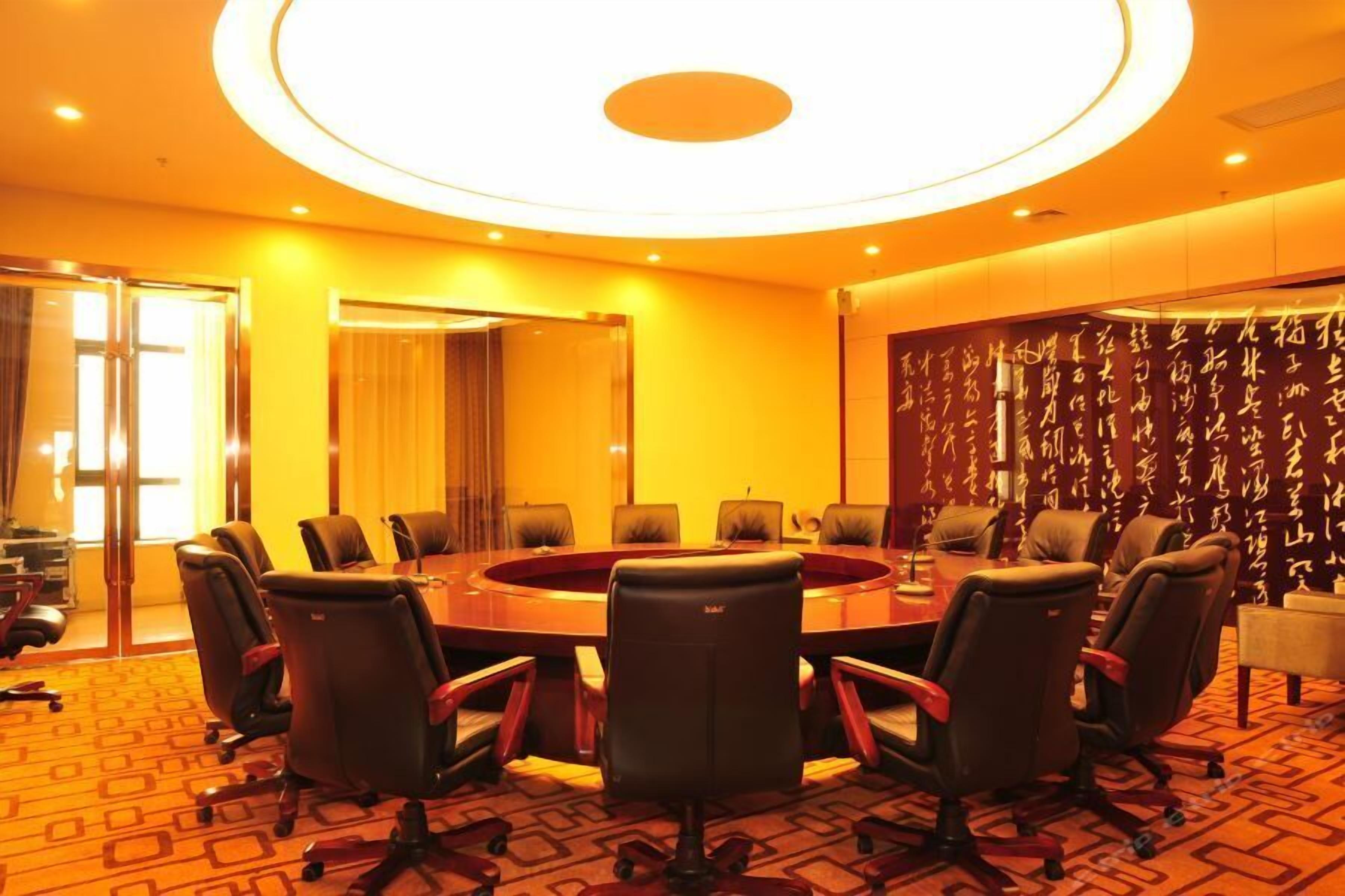 A conference room with a round table, multiple chairs, and a patterned carpet.