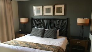 Hotelkamer met een groot bed, twee nachtkastjes, een hoofdbord en drie ingelijste foto's aan de muur.