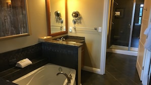 Een badkamer met een bad, een wastafel met spiegel en een douchehoek.
