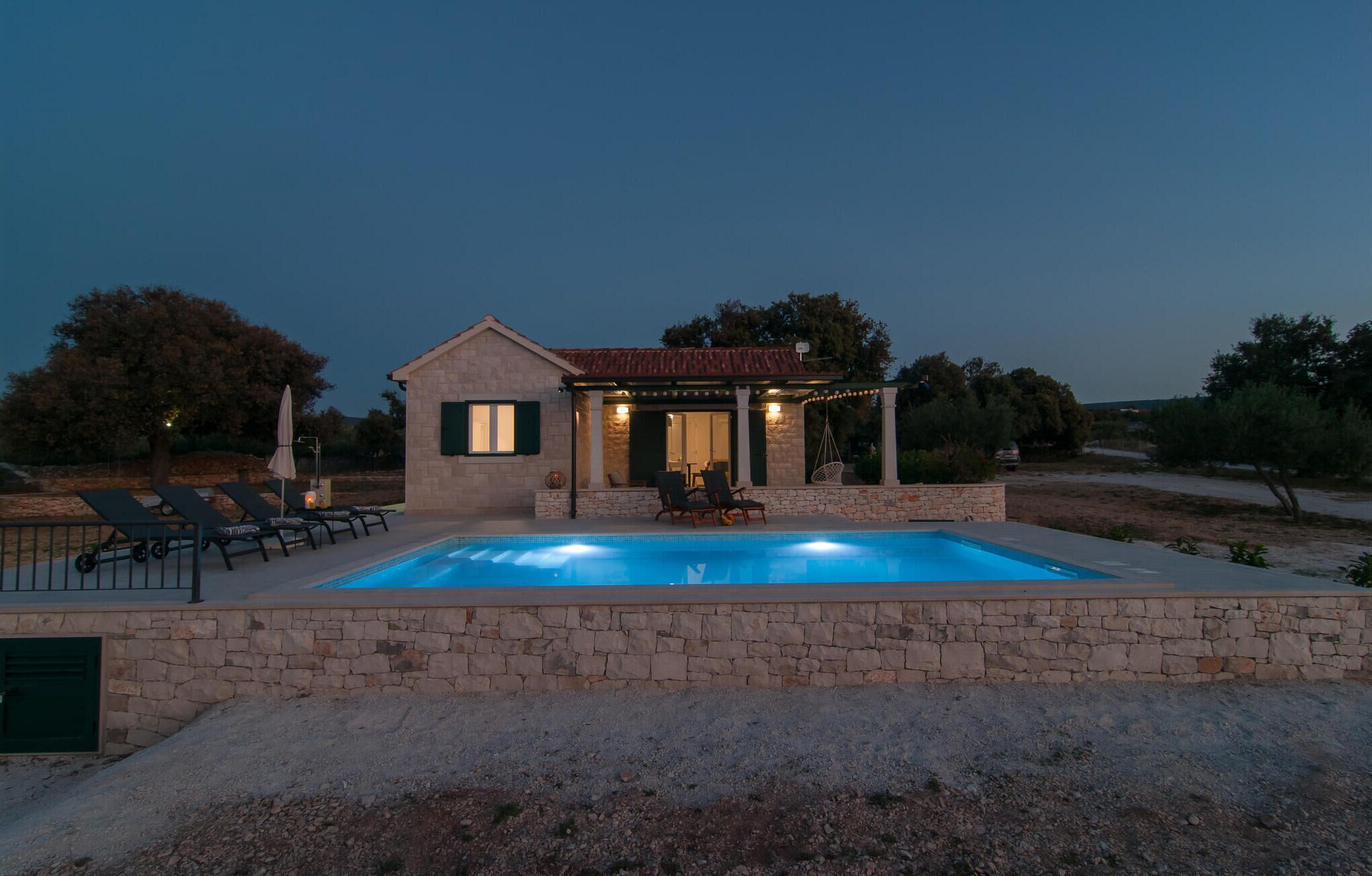 Ein Steinhaus mit Pool, Sitzgelegenheiten im Freien und einer Pergola.