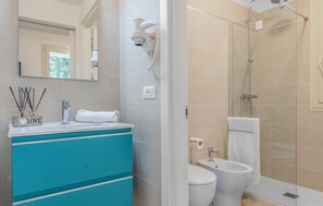Ein Badezimmer mit Waschbecken in Weiß, einem blauen Waschtisch, einer Toilette und einer Duschkabine.