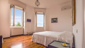 Une chambre à coucher avec un lit, une table de chevet avec une lampe, une télévision et une fenêtre donnant sur le ciel et les montagnes.